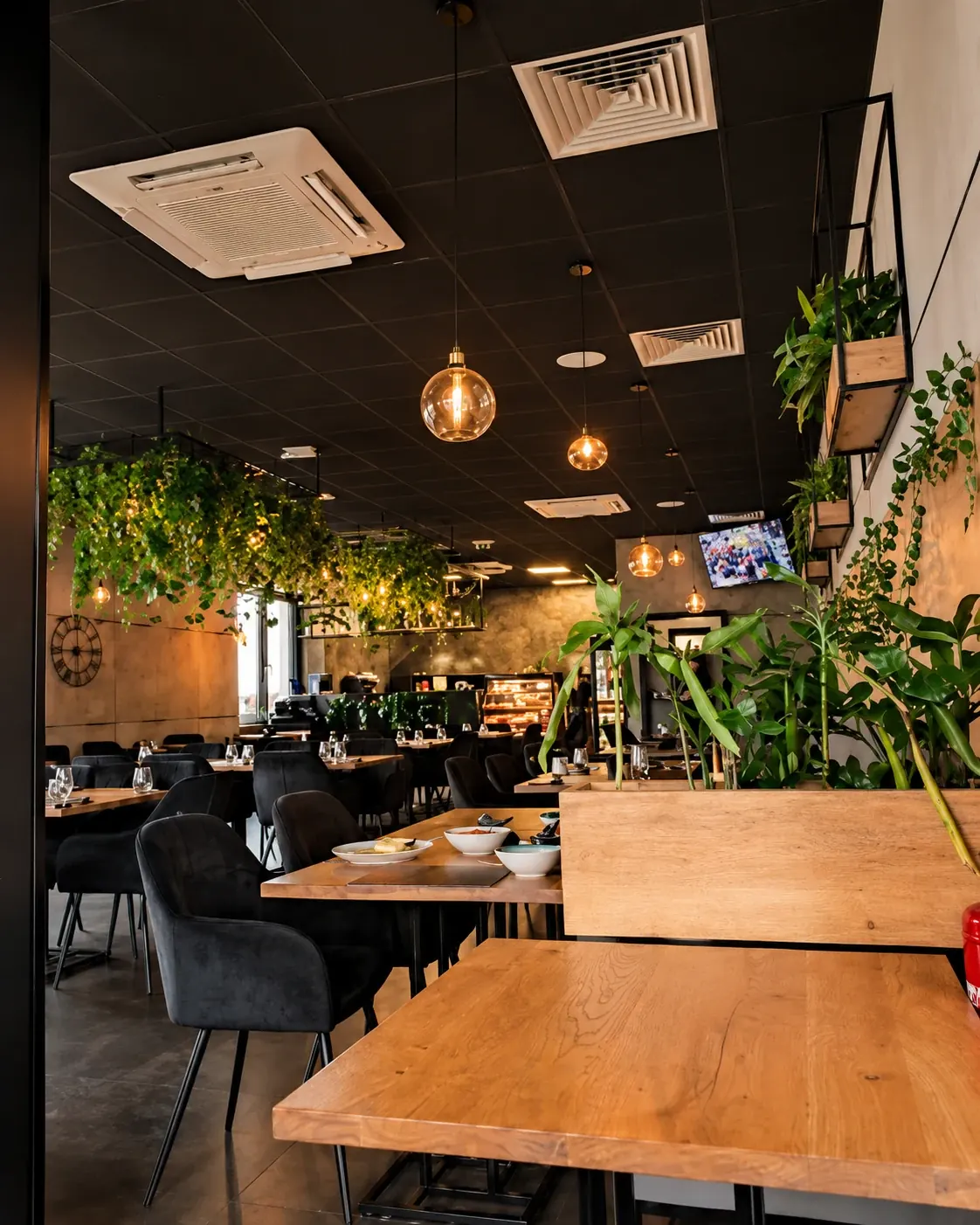 Wnętrze Restauracji Czarny Piec Kościan z zielenią i stolikami